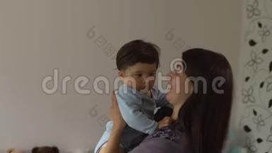 母亲抱着玩她的小儿子和他说话-亚洲混血儿男孩穿着蓝色体恤，